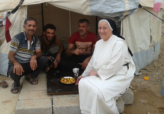 Sister in robes sitting outside tent in Iraq with 3 Iraqi men