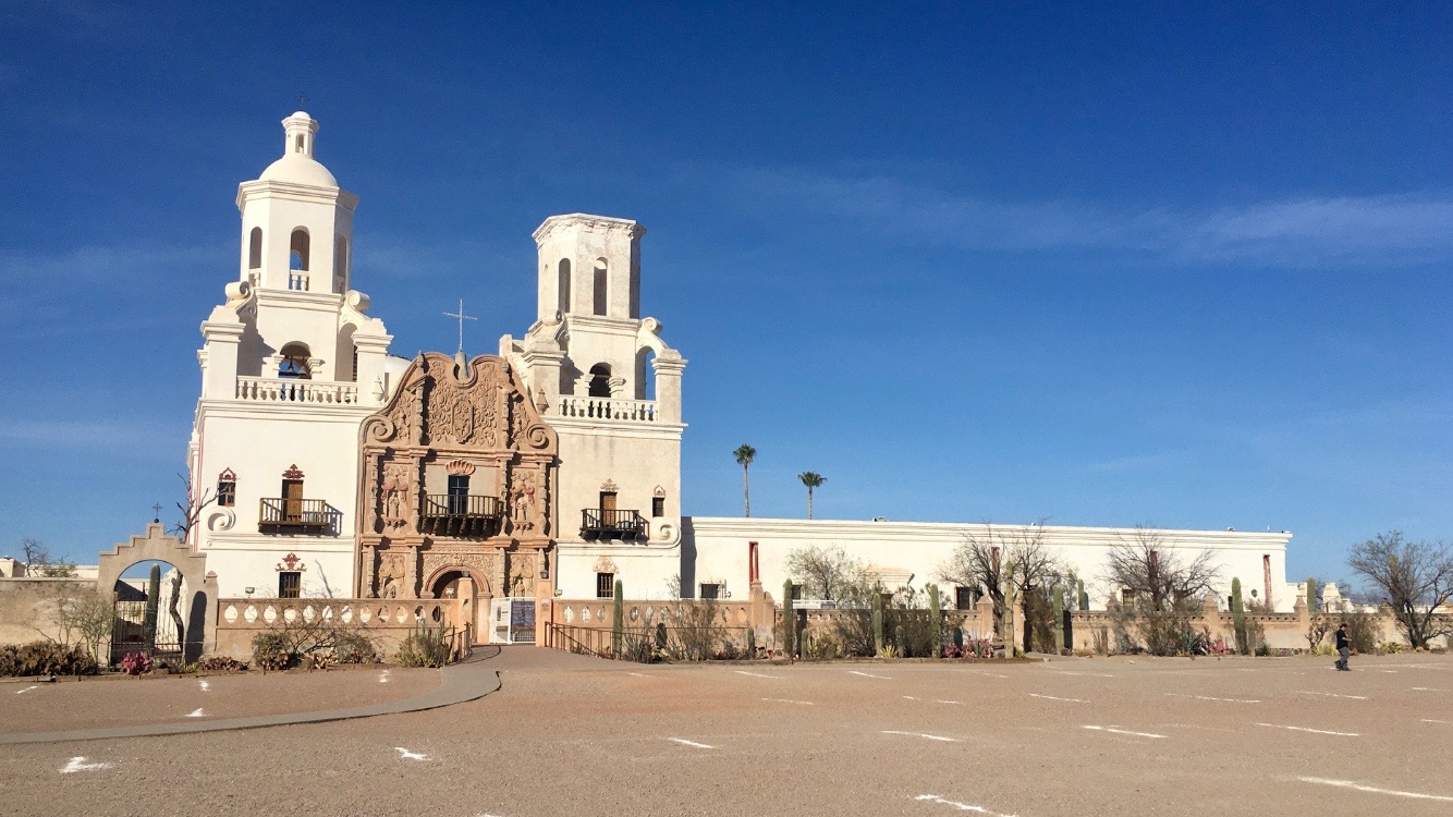 Sun shines on the white stucco facade of San Xavier Mission church in Tuscon, Ariz.