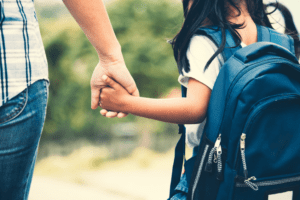 mother holding young girl's hand before school