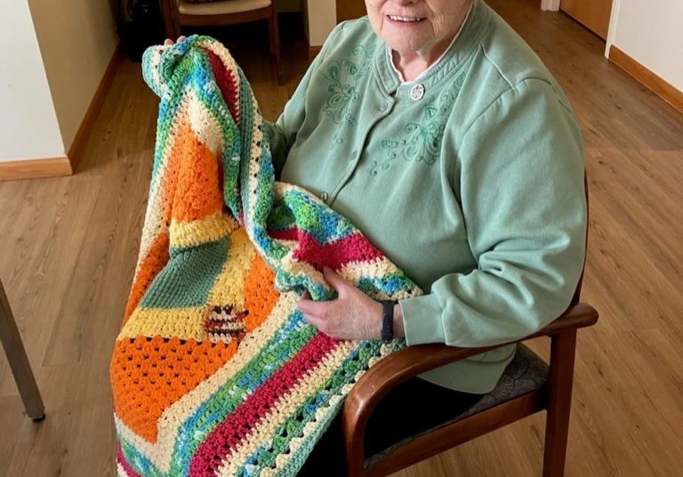 Sister Linda Hayes shows a blanket she knitted using vibrant southwest colors.