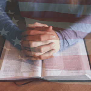 Folded Hands over Bible with US Flag
